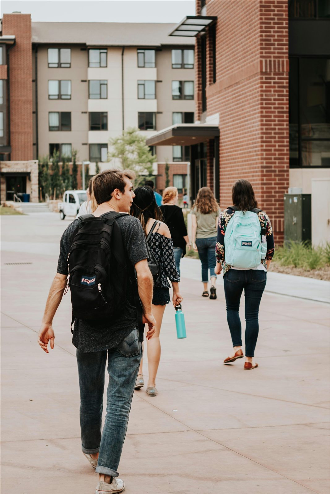 Students walking across campus with backpacks in the morning